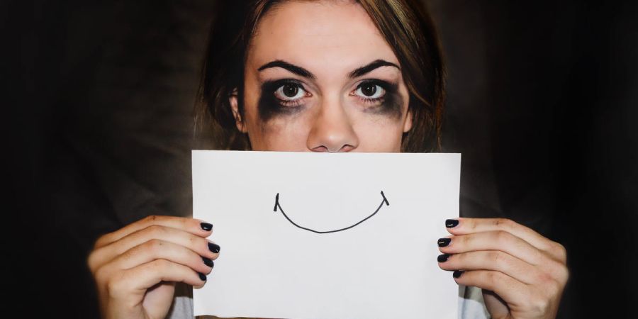 hurt woman hiding behind a smiling sign