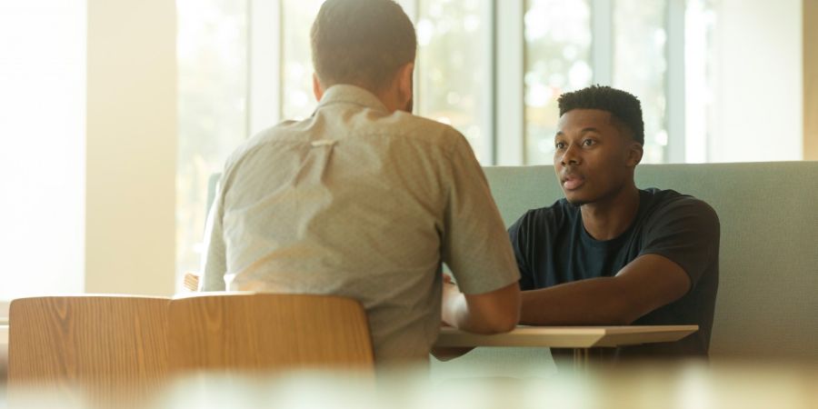 two men talking indoors at a table