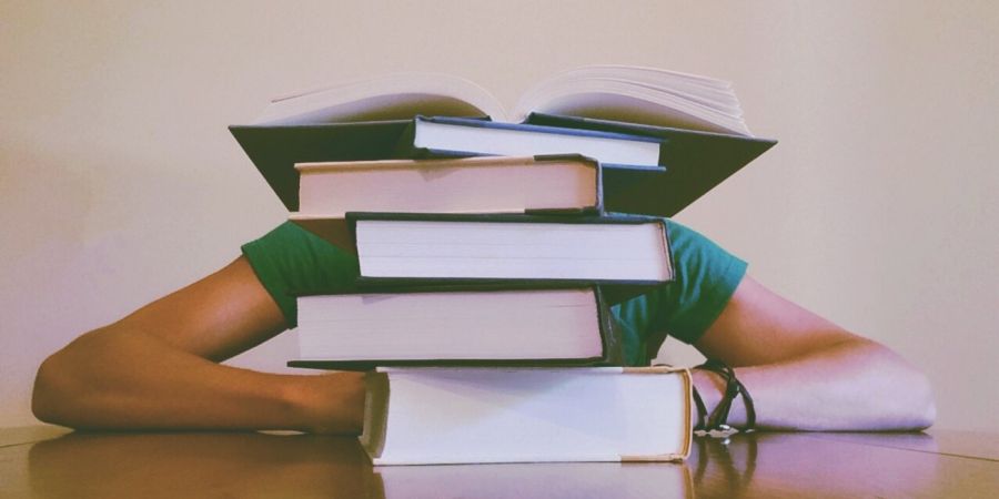 student with a pile of books on the table
