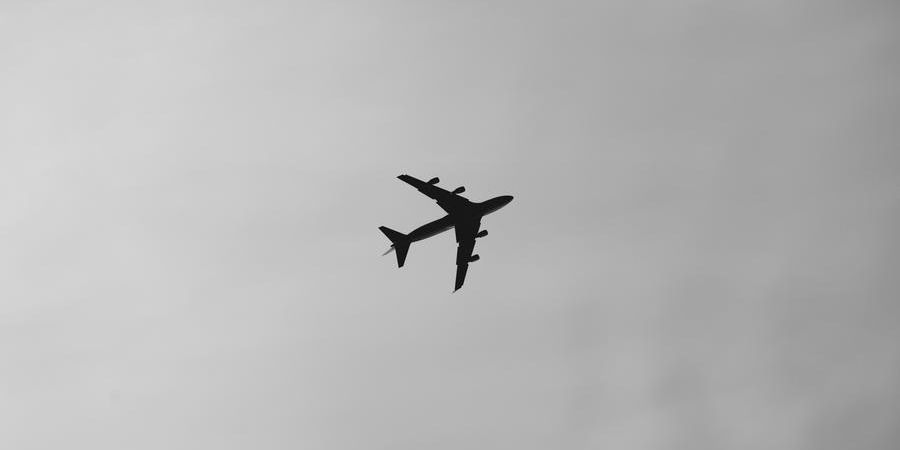 airplane in the sky, outdoors, black and white