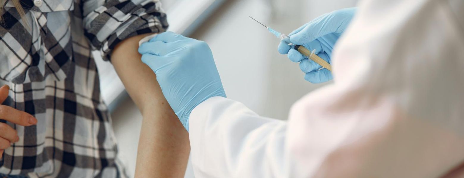 doctor with blue gloves giving person a covid vaccine, indoors