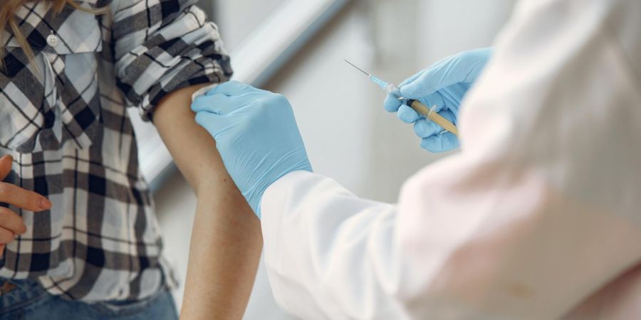 doctor with blue gloves giving person a covid vaccine, indoors