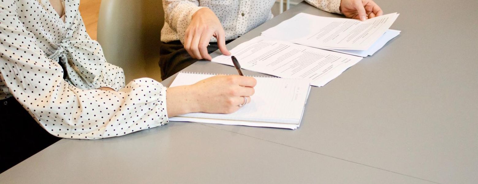 Women signing papers at a table indoors