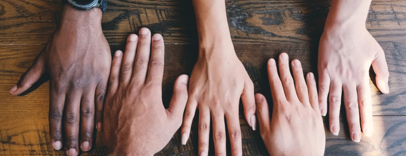 hands of different people on a wooden table indoors