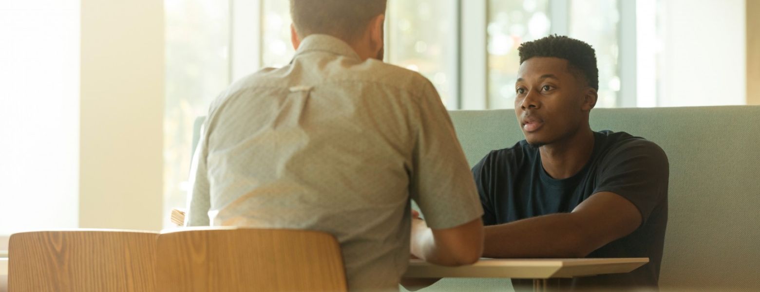 two men talking indoors at a table