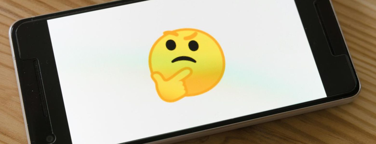 wondering emoji on phone, on wood table, indoors