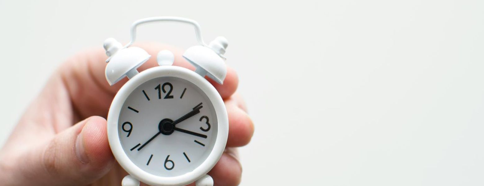 mini white analog clock being held, indoors