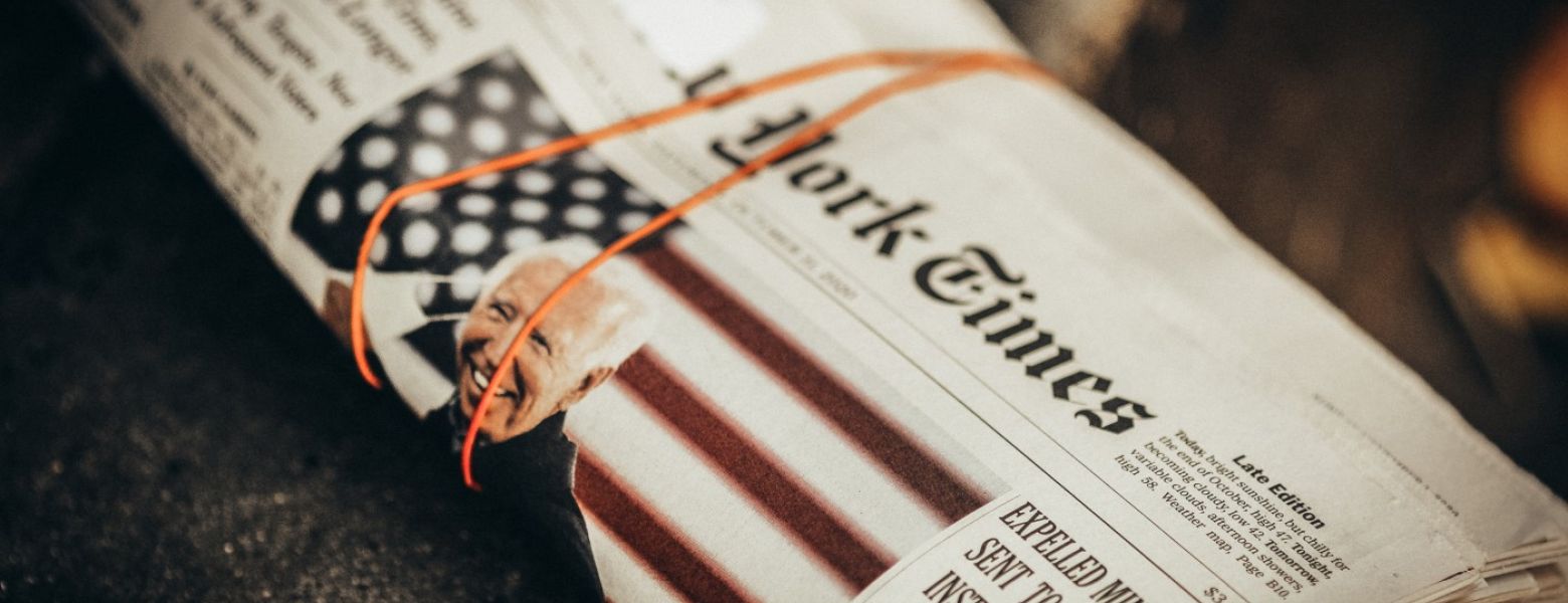 biden on the front of the new york times rolled up paper with rubber band