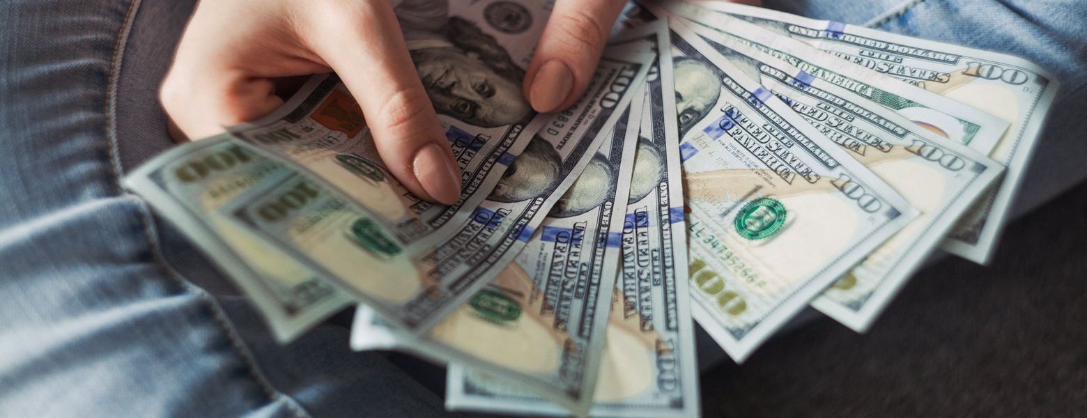 woman holding hundred dollar bills indoors