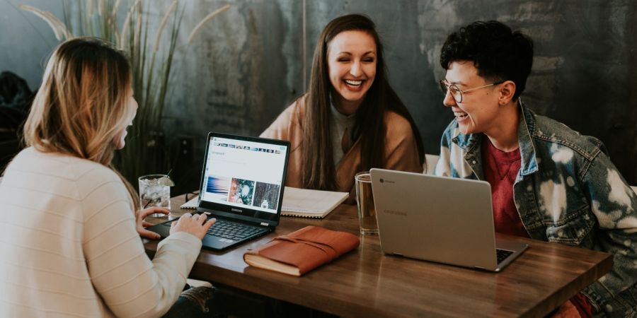 Group of people talking indoors with computer laptops