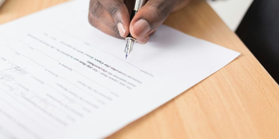 signing a document on a wooden table indoors