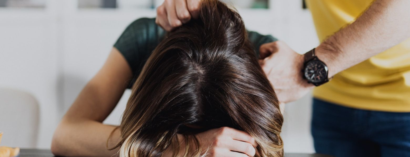 woman's head pressed down on table by a man indoors