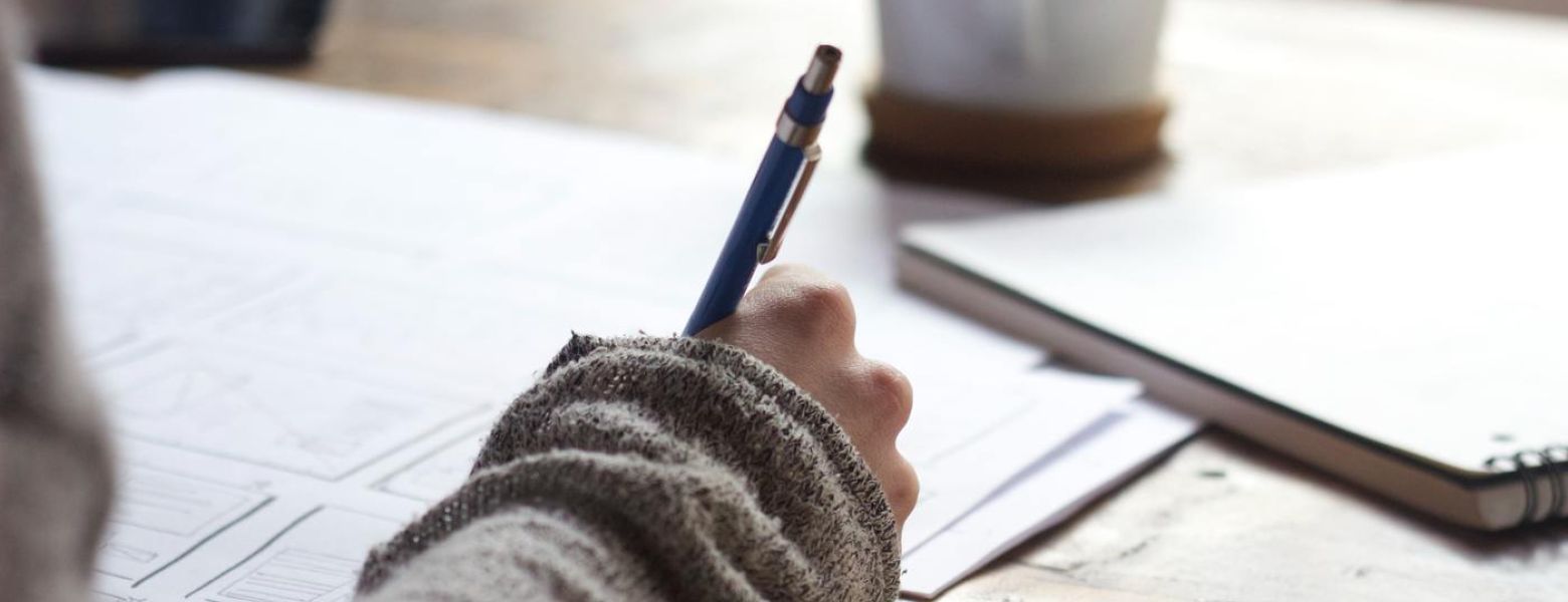 lady with a pen indoors writing something, at a desk