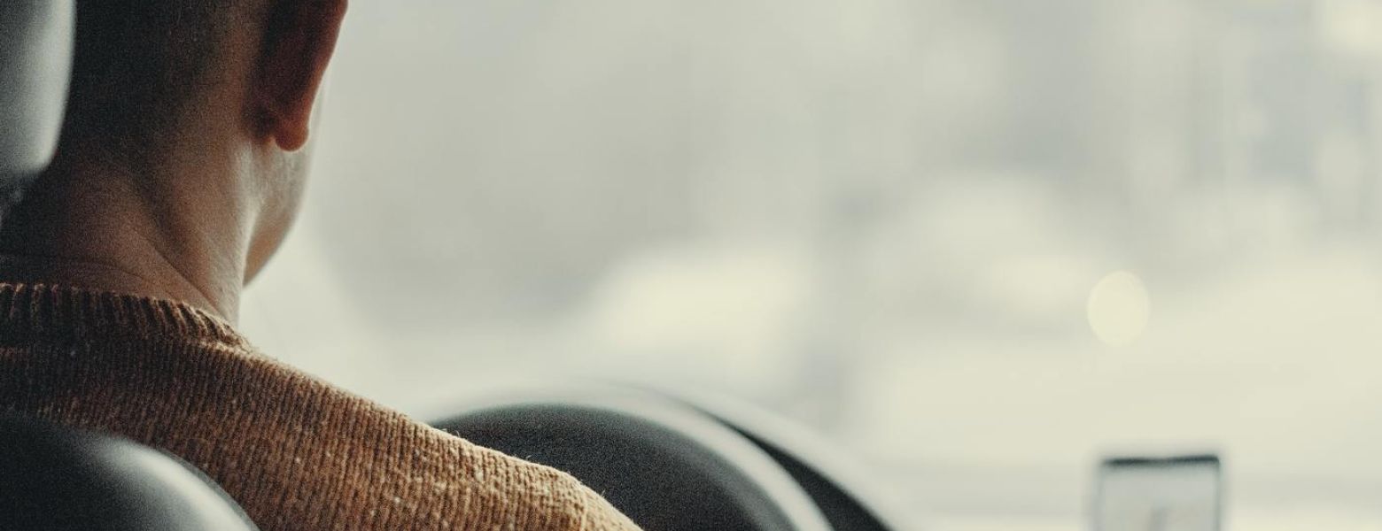 man driving a card with a phone on the dashboard