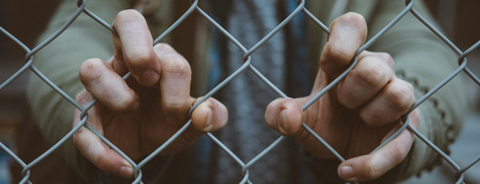 man holding a chain link fence, outdoors