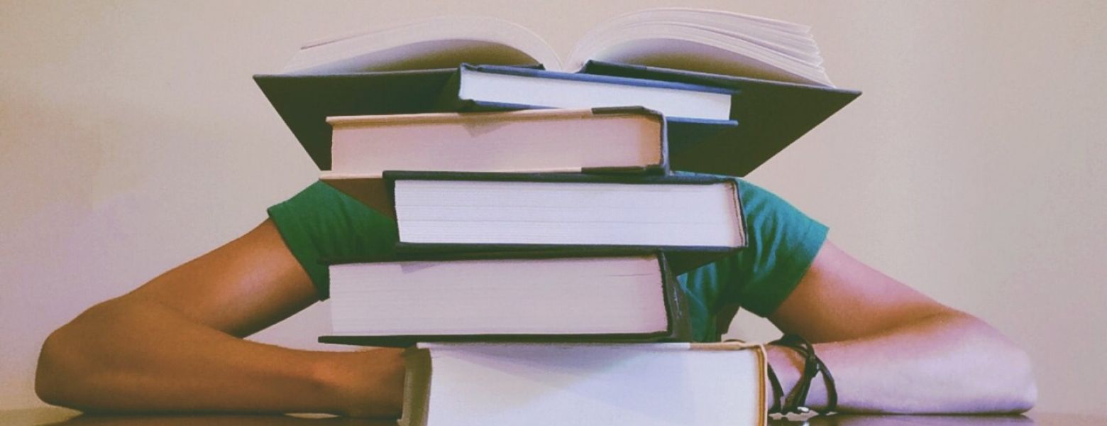 student with a pile of books on the table