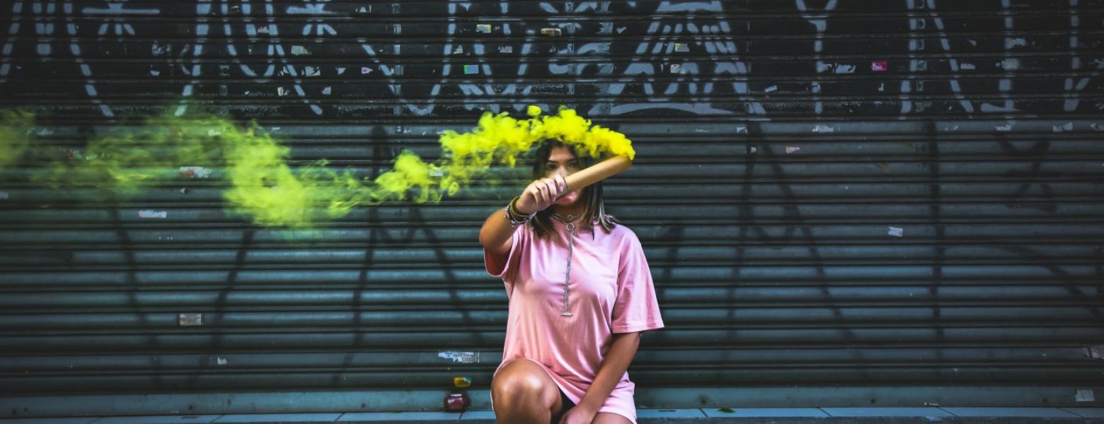 person kneeling outside with a yellow smoke stick
