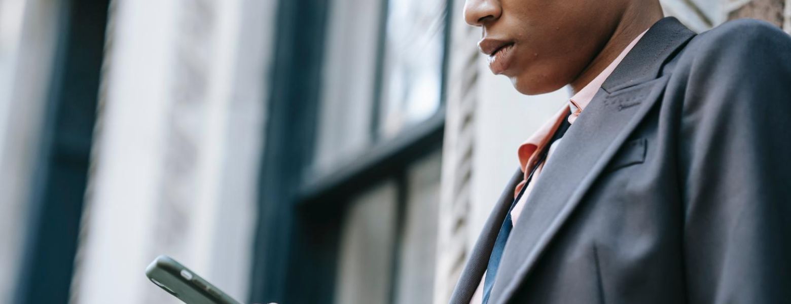 woman looking at her smart phone, in a suit outdoors