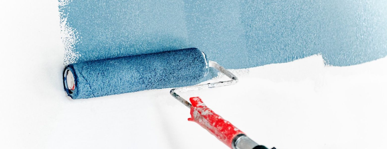 paint roller painting a white wall blue