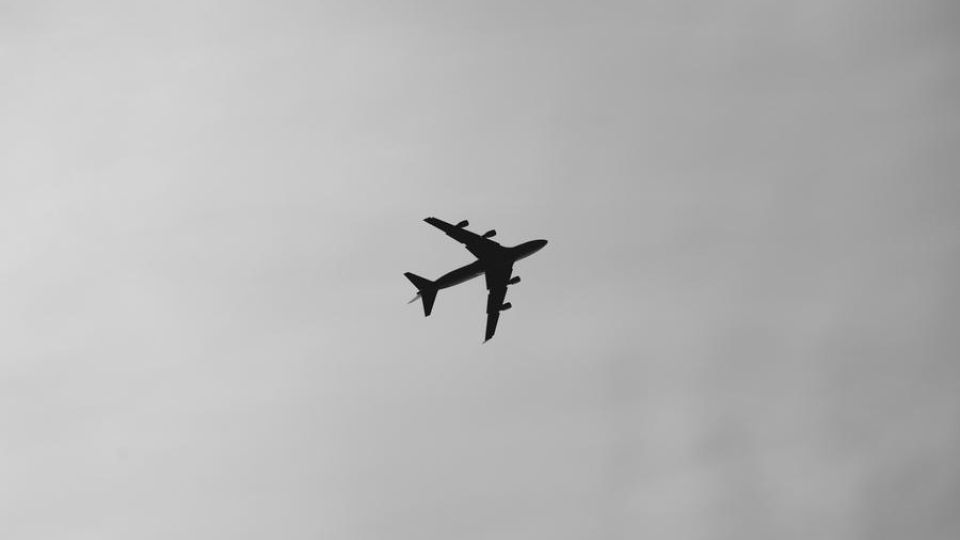 airplane in the sky, outdoors, black and white