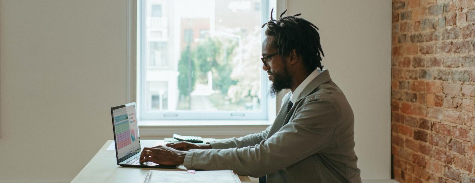 Man typing on a laptop indoors by a window