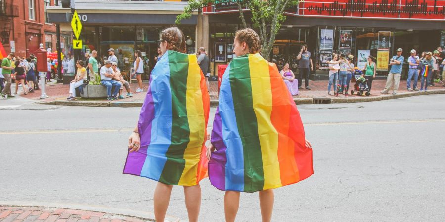 Two women wear rainbow flags on Congress Street in Portland, Maine during the annual Pride parade
