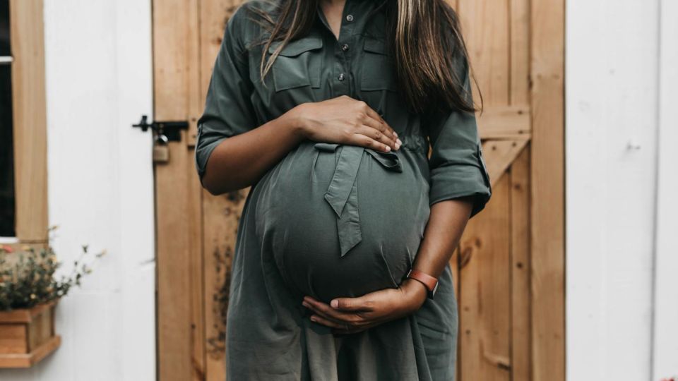 woman holding her pregnant belly outside