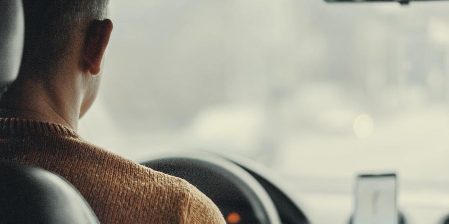man driving a card with a phone on the dashboard