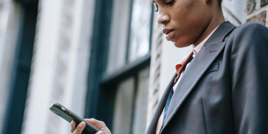 woman looking at her smart phone, in a suit outdoors