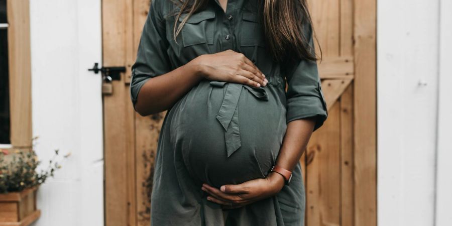 woman holding her pregnant belly outside