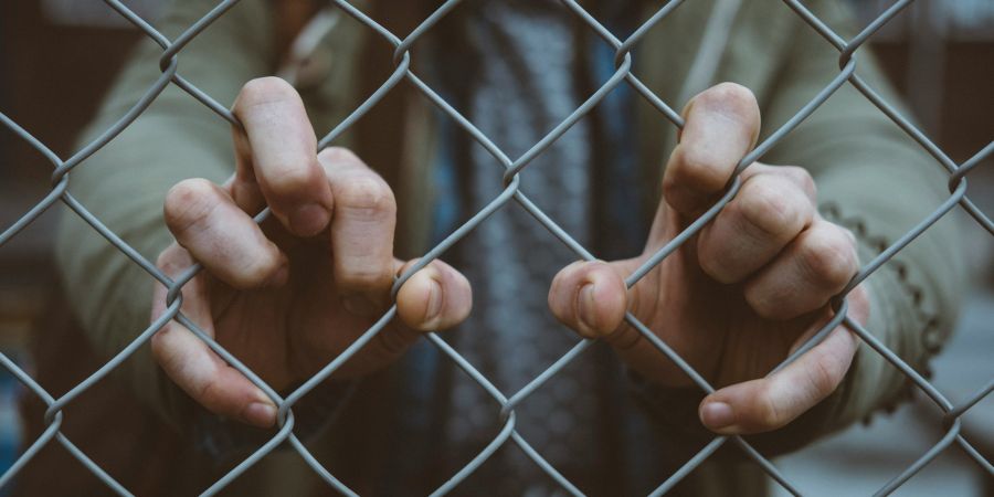 man holding a chain link fence, outdoors