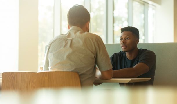 two men talking indoors at a table