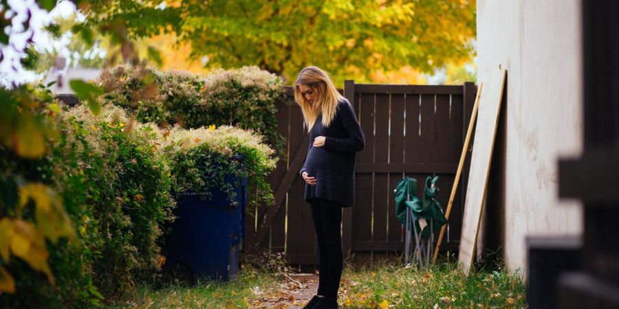 pregnant woman standing outside in yard