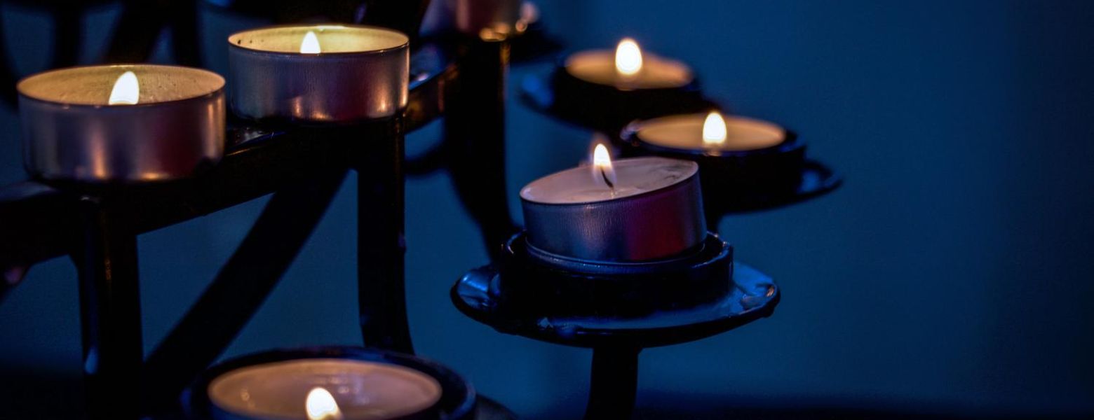candles burning on a rack indoors in the dark