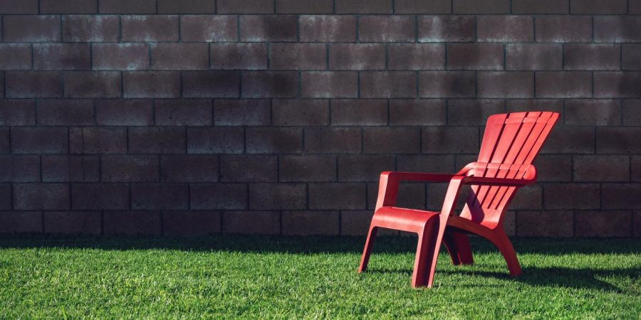 red char on green grass lawn outdoors in front of brick wall