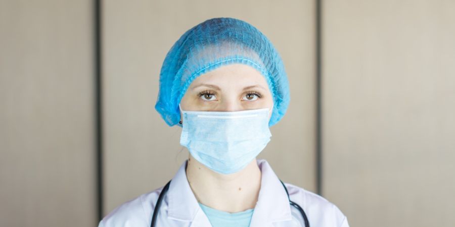 nurse looking at the camera indoors with a hairnet and mask