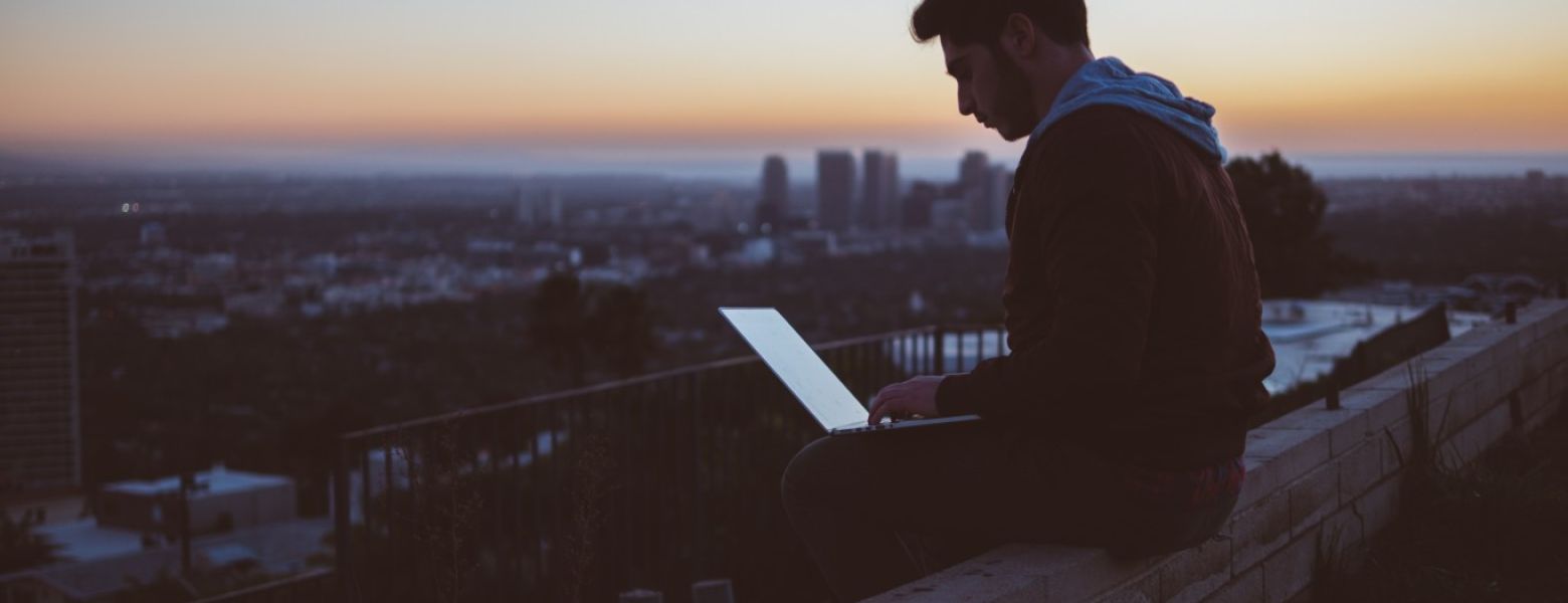 man outside, working on computer laptop