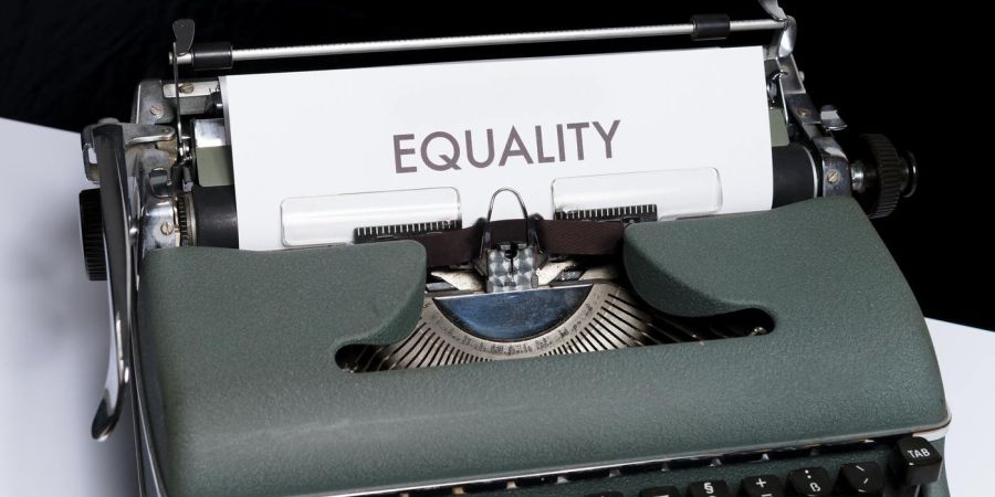 old typewriter with a page that says equality, indoors