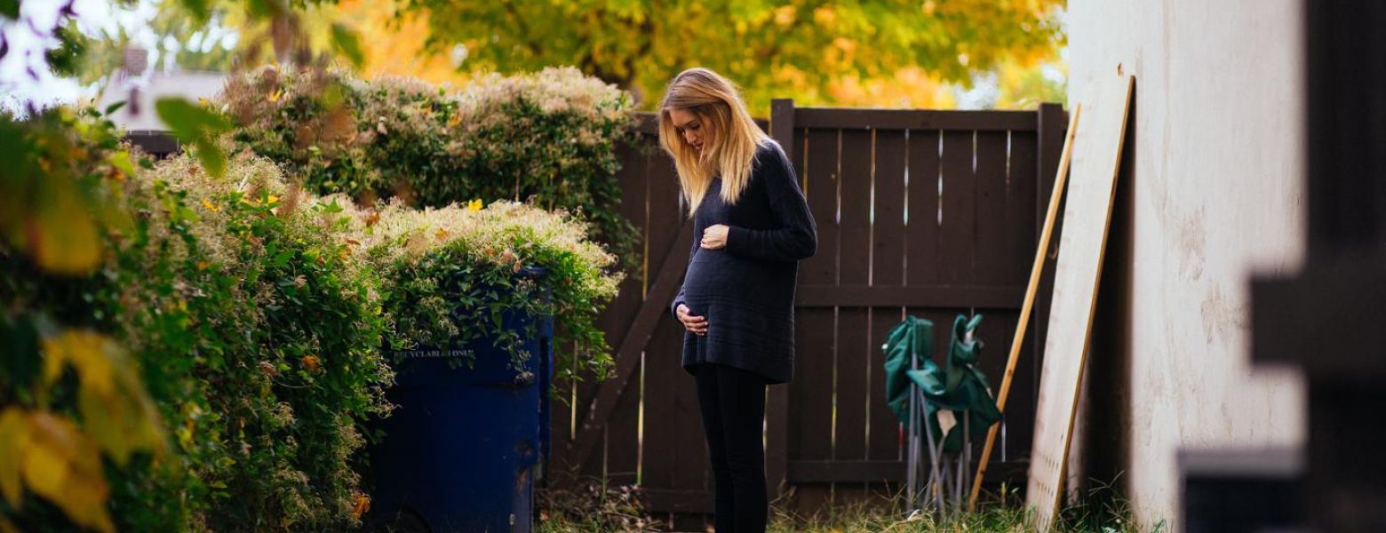 pregnant woman standing outside in yard