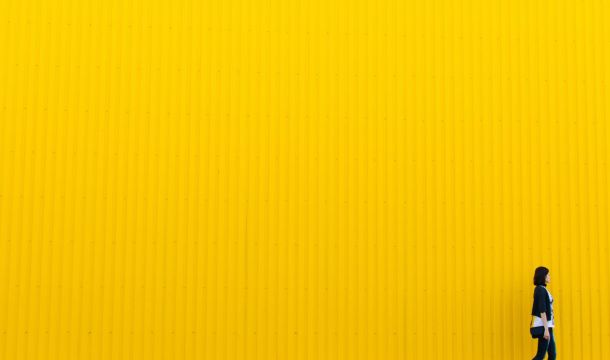 woman walking away, outdoors, yellow wall