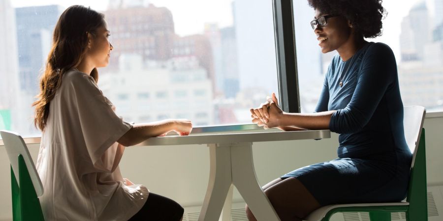 two women interviewing indoors by window
