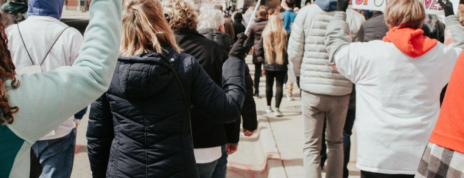 a group of people protesting outdoors, with jackets in the cold