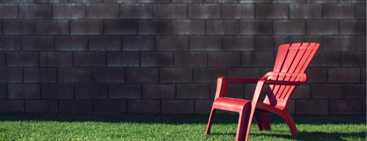red char on green grass lawn outdoors in front of brick wall