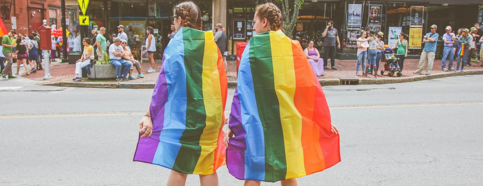 Two women wear rainbow flags on Congress Street in Portland, Maine during the annual Pride parade
