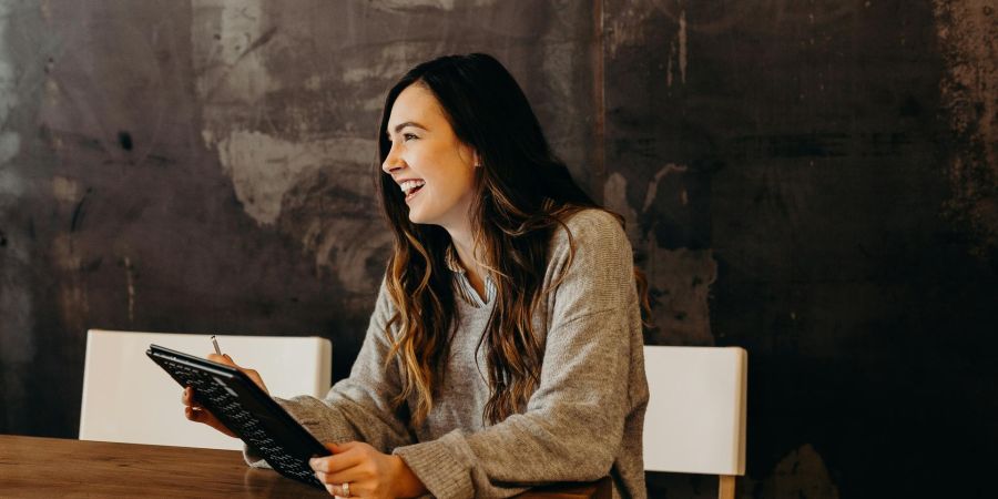 women smiling at a table with a device