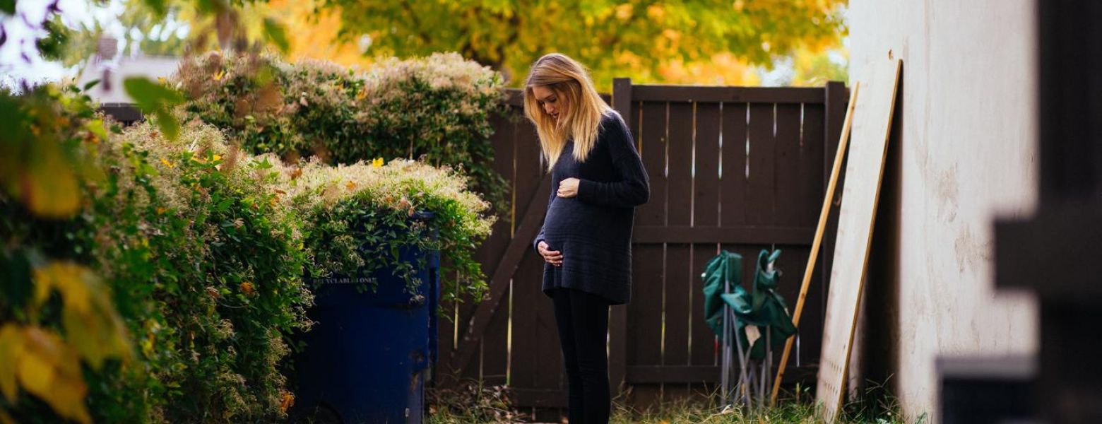 pregnant woman standing outside in yard