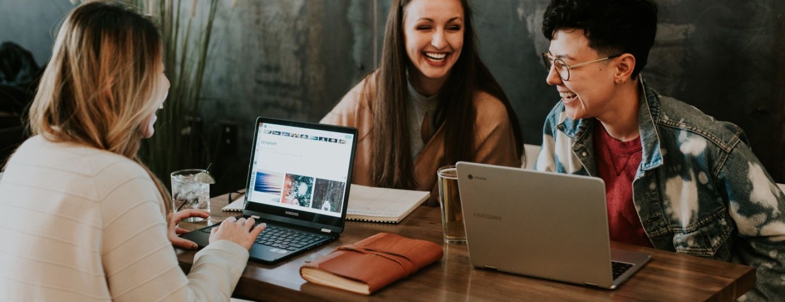 Group of people talking indoors with computer laptops