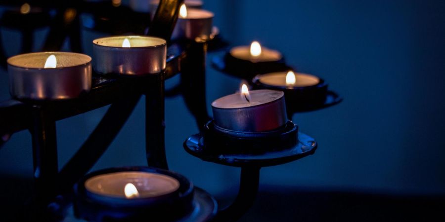 candles burning on a rack indoors in the dark