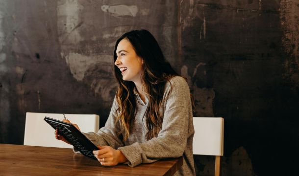 women smiling at a table with a device