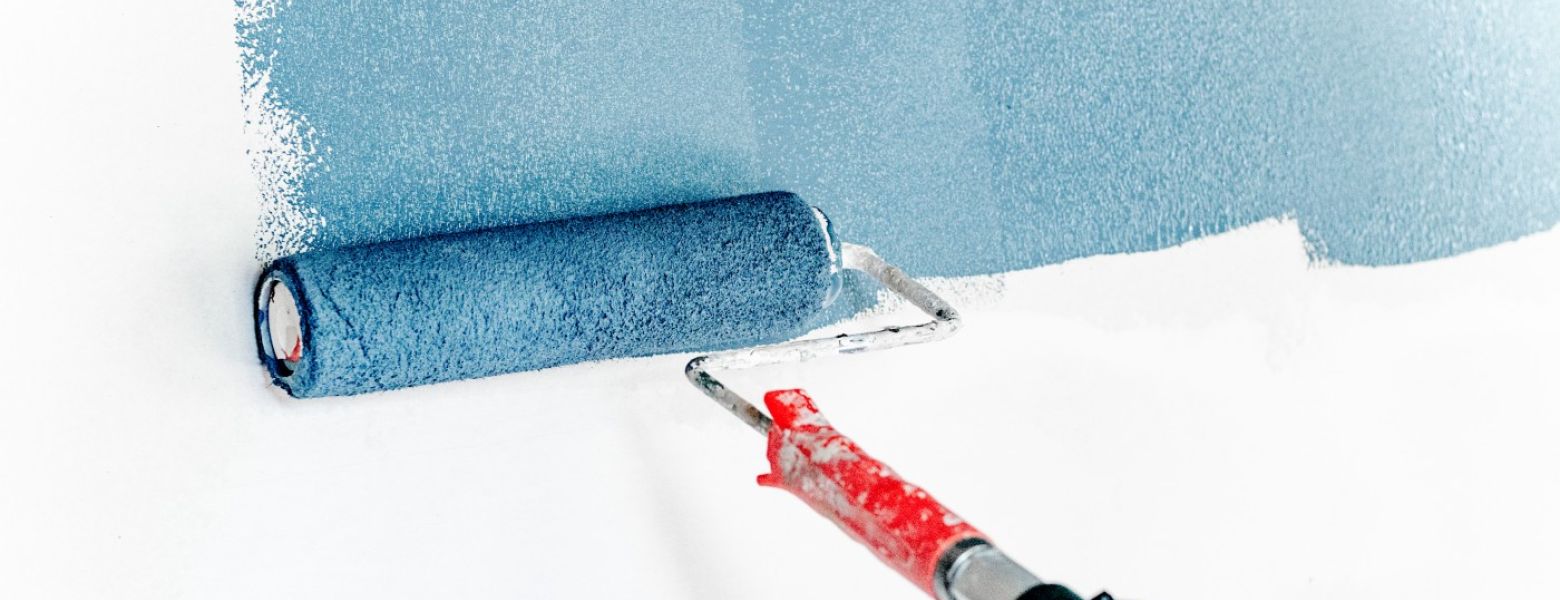 paint roller painting a white wall blue